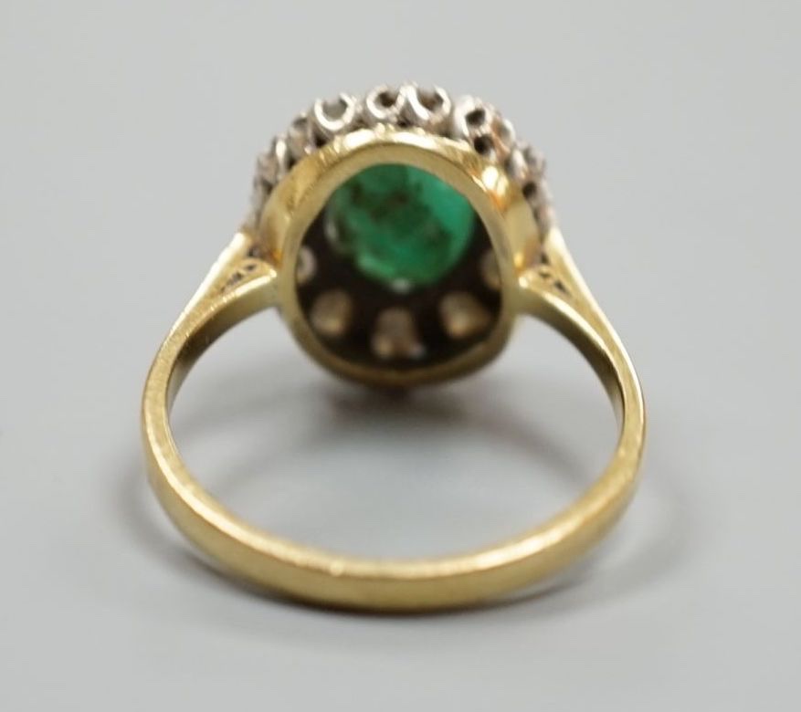 A yellow metal, emerald and diamond set oval cluster ring, size P/Q, gross weight 5 grams.